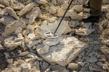 Tarihi değerleri araştıran metal dedektörlü bir adam.