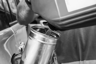 Erkek işçi dizel yakıta bir katkı ekler. Yanma verimliliğini arttır. Bir erkek el, bir teneke kutudan arabaya yakıt dolduruyor.