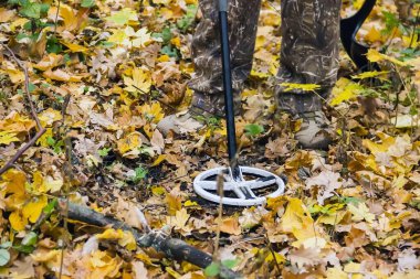 Tarihi değerleri araştıran metal dedektörlü bir adam.