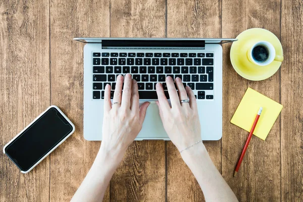 Yaratıcı uzaktan kumandalı ofis işleri için bilgisayar laptopu kullanımı. Genç bir kadın modern dijital etkin şirket için klavye ve akıllı telefon kullanıyor..