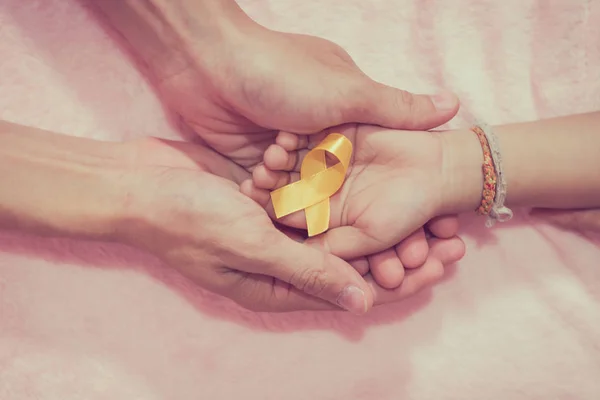 Mature hands and boys cancer surgery symbol ribbon, view from above.