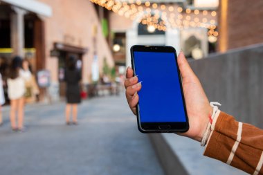 Sokakta yürürken akıllı telefonu tutan Asyalı kadın.