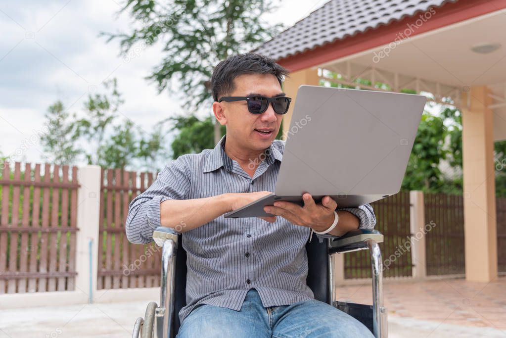 Disabled middle-age Asian person in the wheelchair work at home 