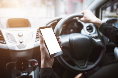 Asyalı erkekler bir araba sürerken bir cep telefonu tutarak.