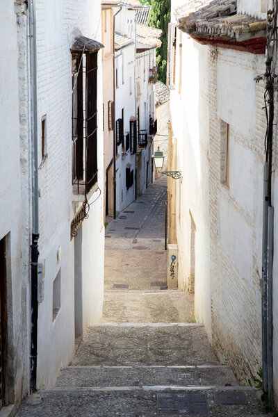 Granada, Spain - May 27, 2019: A narrow alley with white houses in the historic Albaicin district .