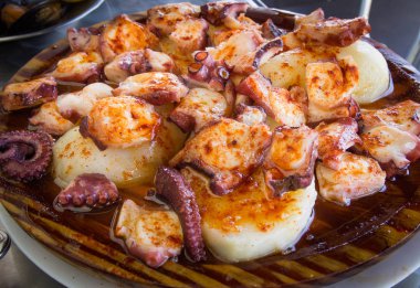 Ahtapot ve patates ahşap plaka üzerinde kırmızı biber ve zeytin yağı ile pişirilir. Galiçyaca gıda