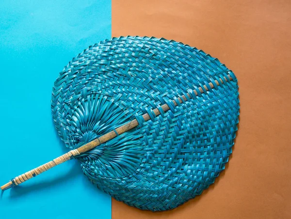 Blue straw fan on blue and brown background