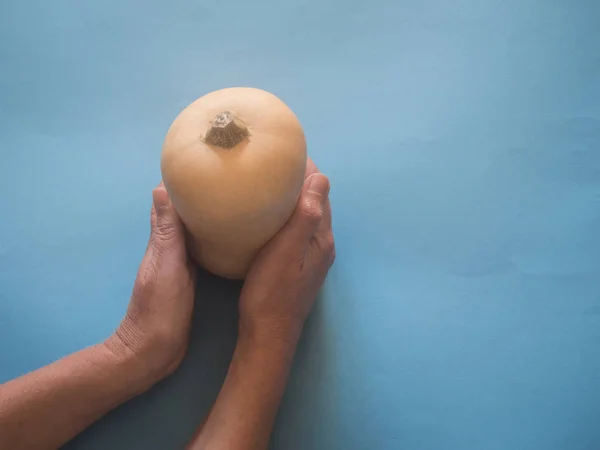 バターナット カボチャ青の背景に手 — ストック写真