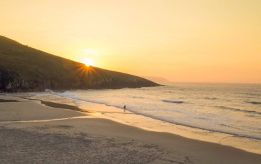 Günbatımında sahilde yürüyüş kişi