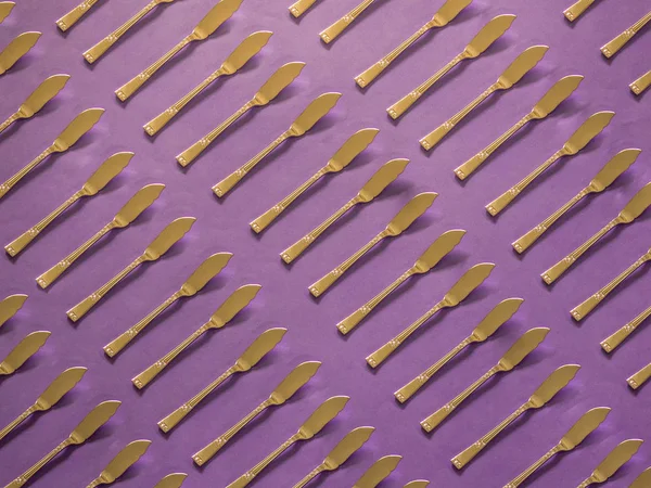 Gold spread knives pattern on pink background