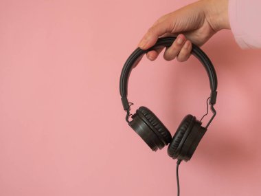 Kopyalama alanı ile pembe arka planda el tutma kulaklıkları