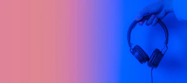 Hand hält Kopfhörer auf blau und rot mit Kopierraum — Stockfoto