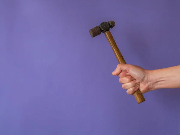 Mano con martillo sobre fondo púrpura con espacio para copiar —  Fotos de Stock