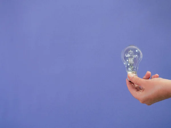 Hand with light bulb    on purple background and copy space - co