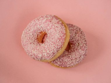 Pembe arka planda beyaz serpiştirilmiş pembe çörekler.