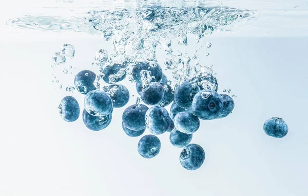 一群蓝莓溅到水面上下沉。隔离在白色背景, 飞溅食品摄影. — 图库照片