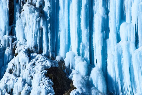 Grandes icicles pendurados no penhasco da margem do rio . — Fotografia de Stock