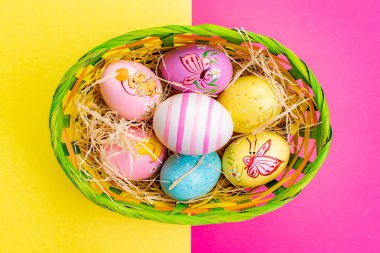 Paskalya yumurtası ile hasır sepeti renk masa arka planda boyalı el