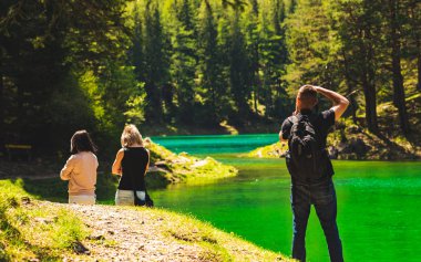 Styria 'da yeşil gölde kamera ile Hiker Lake Shore boyunca yürüyüş iki kız fotoğraf.