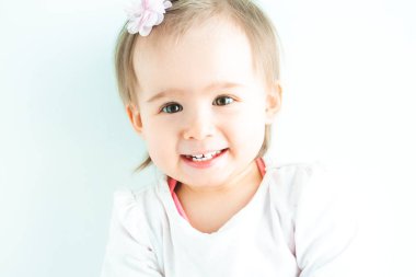 Duvara karşı büyük gözleri olan bebek kız. Kamera ve gülüyor bakarak