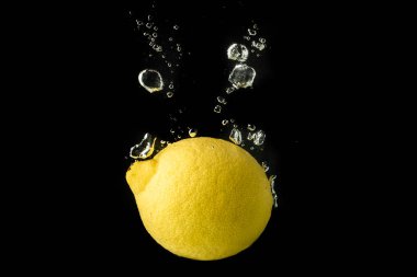 Limon meyve su içine sıçrama ve siyah arka plan üzerinde izole batıyor