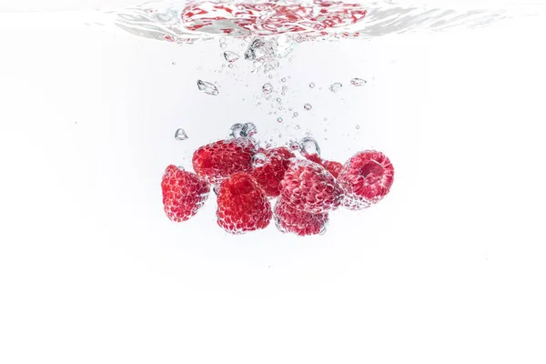 Himbeeren spritzen mit Luftblasen in kristallklares Wasser — Stockfoto