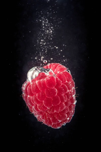 Raspberry falling into a water — Stock Photo, Image