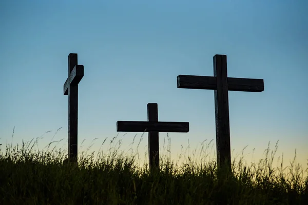 Three crosses on a hill with grass