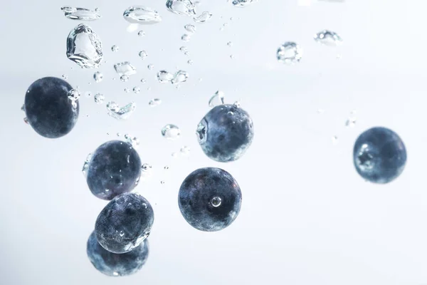 Arándanos orgánicos hundiéndose en el agua con burbujas de aire —  Fotos de Stock