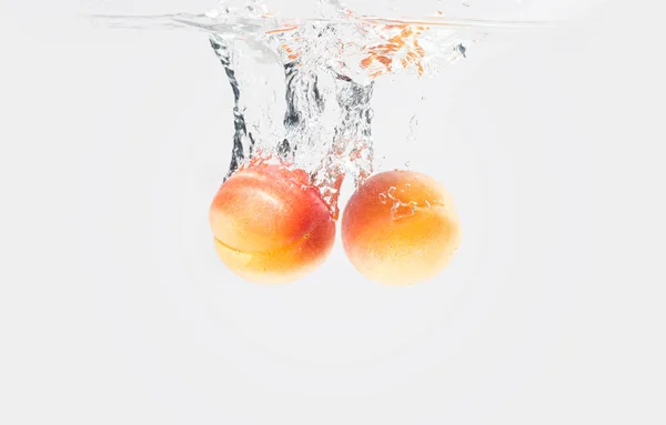 Two apricots dropped water with splash — Stock Photo, Image