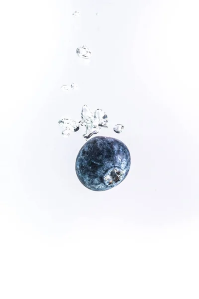 一个有机蓝莓掉进清澈的水里. — 图库照片