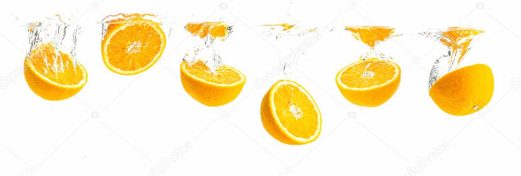 Bunch of organic orange halves sinking into crystal clear water with air bubbles. Panoramic view