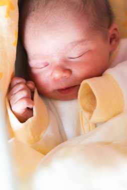 Uyuyan yeni doğmuş bebek. Sevimli küçük kız bir günlük. Battaniye ile kaplı yan yatan sevimli.