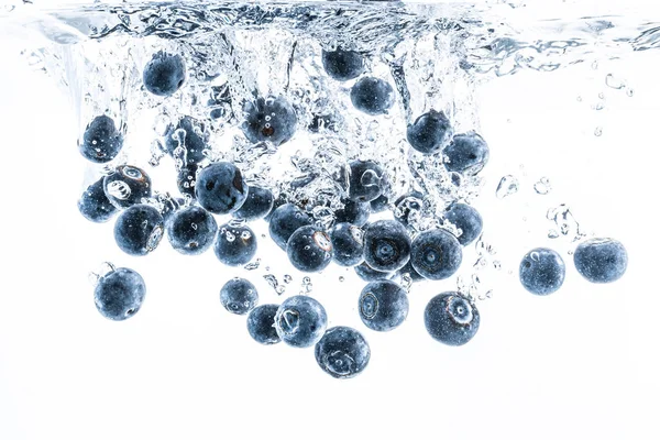 Arándanos frescos que caen en el agua sobre fondo blanco. Frutas salpicando en agua clara . —  Fotos de Stock