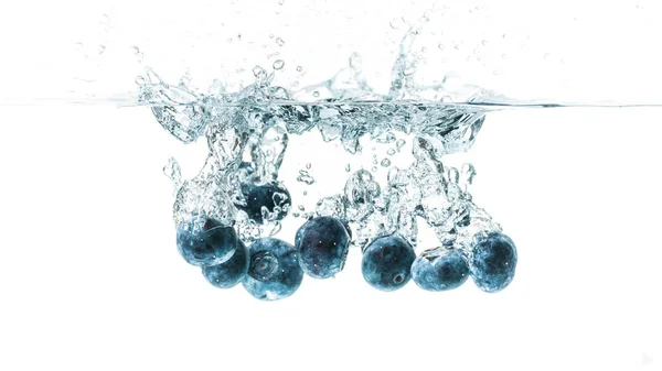 Frische Blaubeeren fallen in Wasser auf weißem Hintergrund. Früchte plätschern ins klare Wasser. — Stockfoto