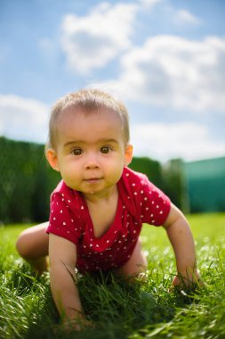 Sevimli bir kız çocuğu bahçede çimlerin üzerinde eğleniyor..