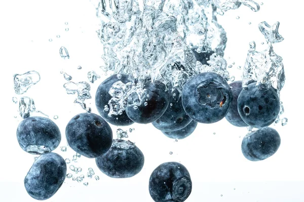 Bleuets coulant dans l'eau avec des bulles d'air fond blanc — Photo