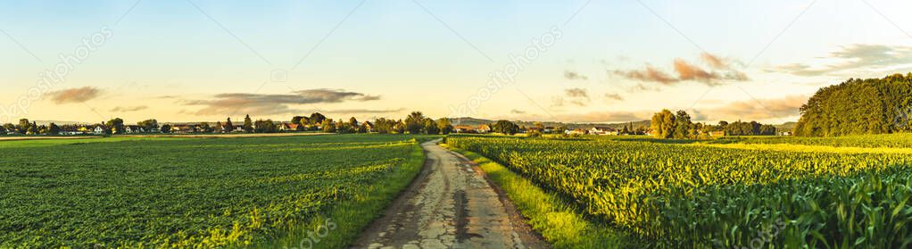 Panorama, sunset over fields and Austrian village with dramatic sky and colorful clouds