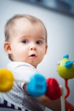 Bir yaşındaki bir bebek renkli eğitim programlarıyla Walker 'da oturuyor. Çocuk gelişimi kavramı