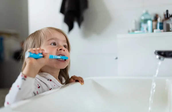 Menina bebê no banheiro brilhante escovando os dentes acima da pia. — Fotografia de Stock
