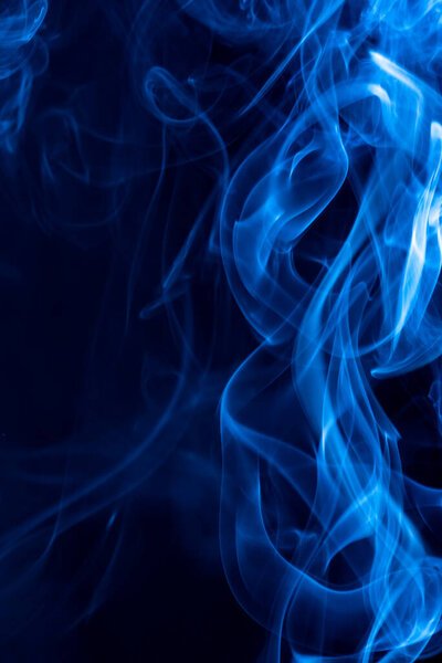 Blue abstract shaped smoke against black background. Abstract background. Selective focus