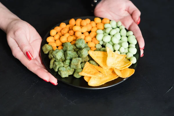 Junk food snacks hands chips peanut crouton plate — Stock Photo, Image