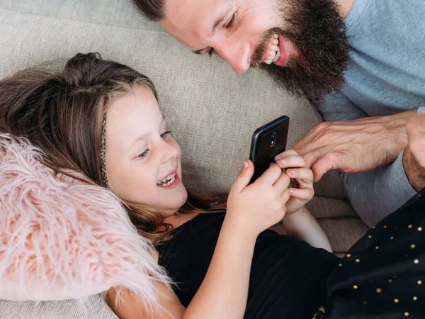 Família lazer menina pai assistir telefone alegria risos — Fotografia de Stock