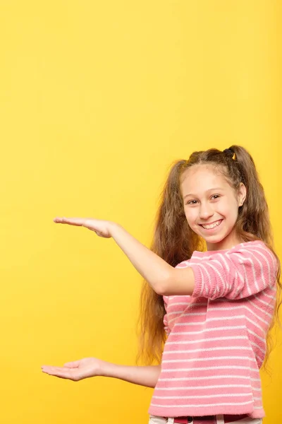 Sorrindo menina segurando grande objeto virtual mão vazia — Fotografia de Stock