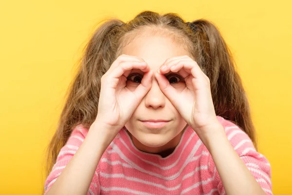 Chica fingiendo mirar binoculares búsqueda de manos —  Fotos de Stock