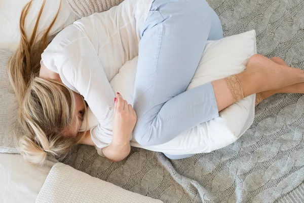 Kobieta uścisk cuddle poduszki leżące poza łóżeczko — Zdjęcie stockowe