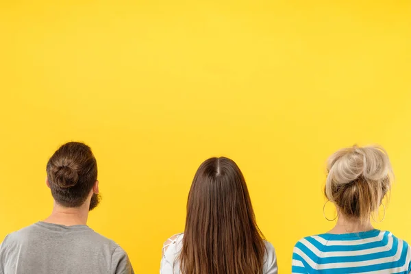 Vista posterior personas de pie fondo amarillo — Foto de Stock