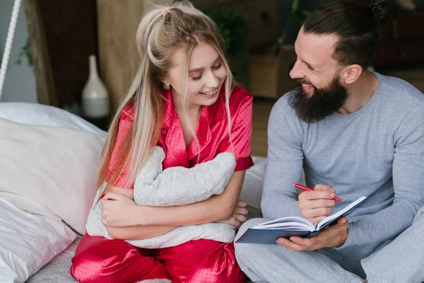 Joven pareja cama aniversario planificación hacer notas — Foto de Stock