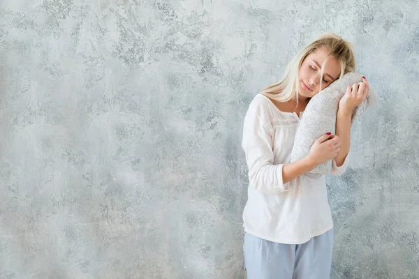 Quality bedding and slepping comfort. Woman stand eyes closed holding soft knit blanket. Copy space on grey textured background.