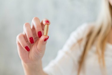 Sağlıklı beslenme ve pill vitamin takviyeleri. Balık yağı kapsül parmakları arasında tutarak bakarak kadın.
